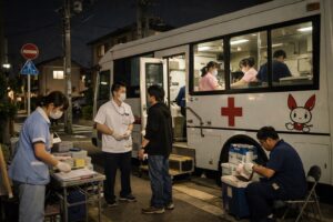 日本の住宅街に停車する夜間稼働中の移動献血バスと医療スタッフの様子